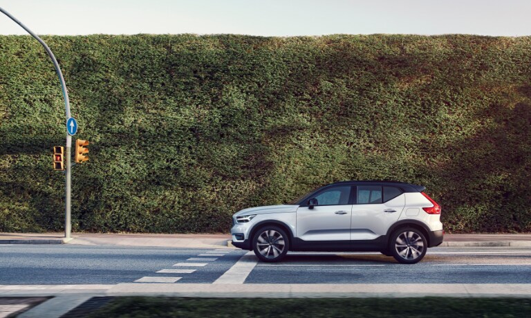 2020 Volvo XC40 Recharge in white stopped at red light with a large bush along the road