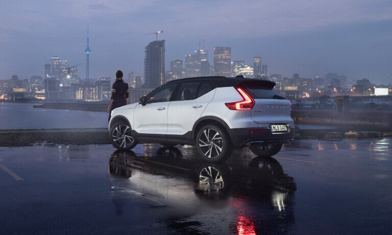 White Volvo parked by the lake on a city skyline