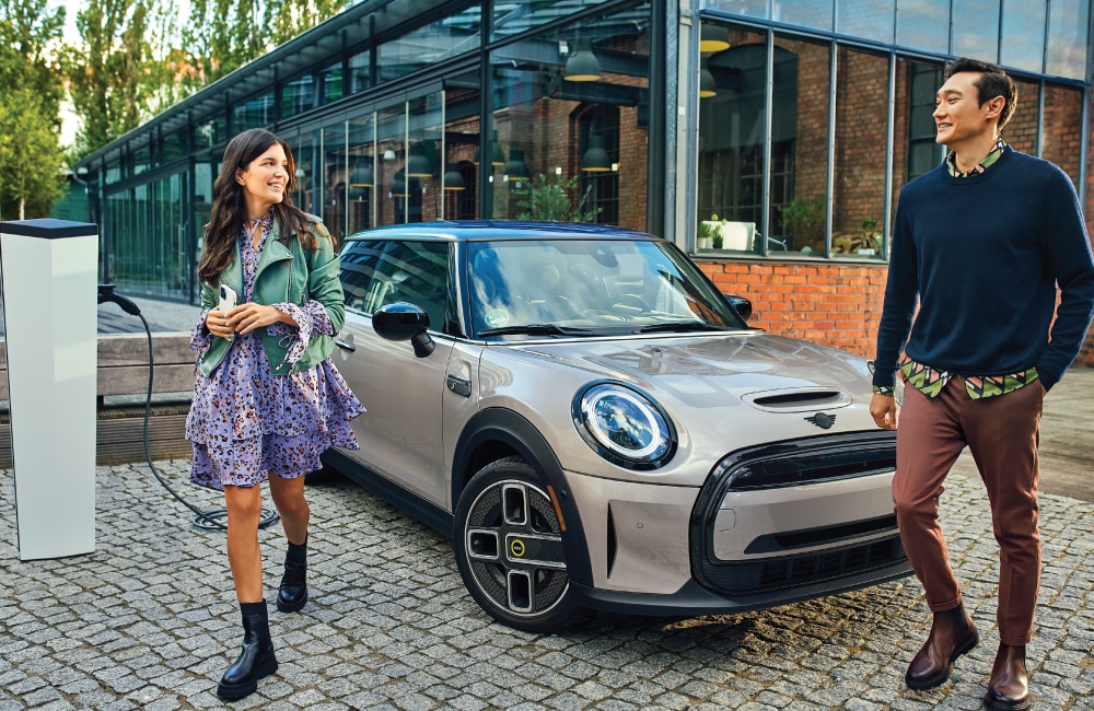 Image-11.png Woman and man stepping out of a MINI Electric while it is charging