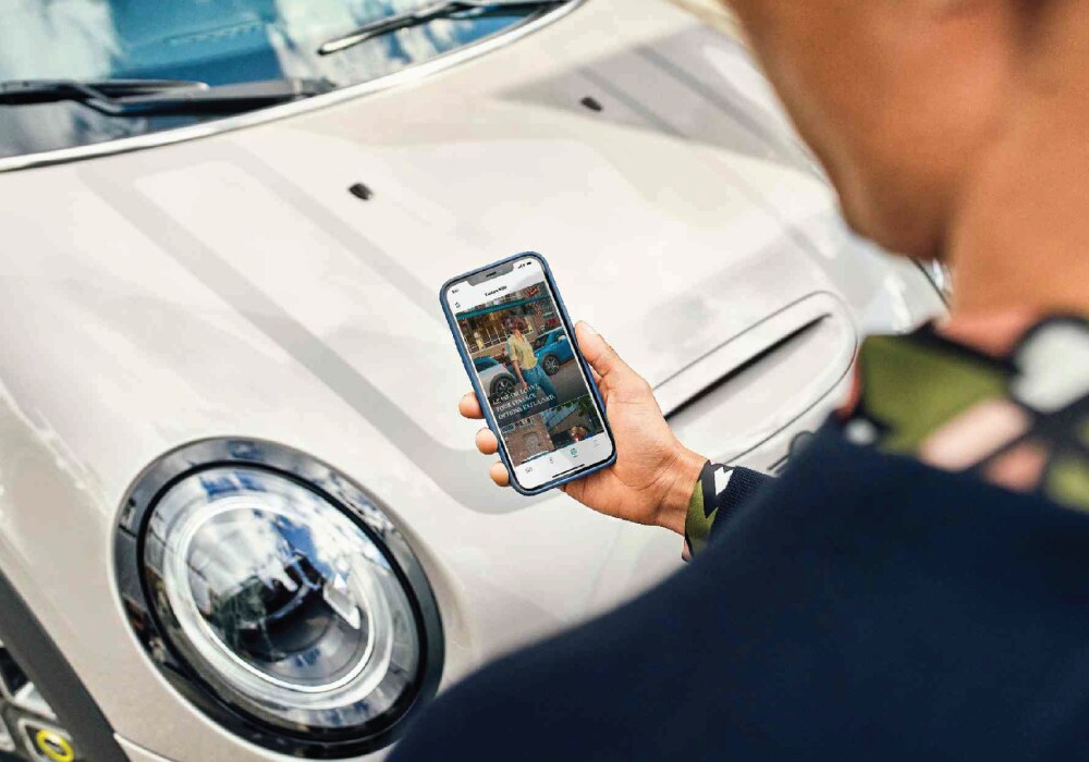 Image-2.png Man looking at phone next to a MINI