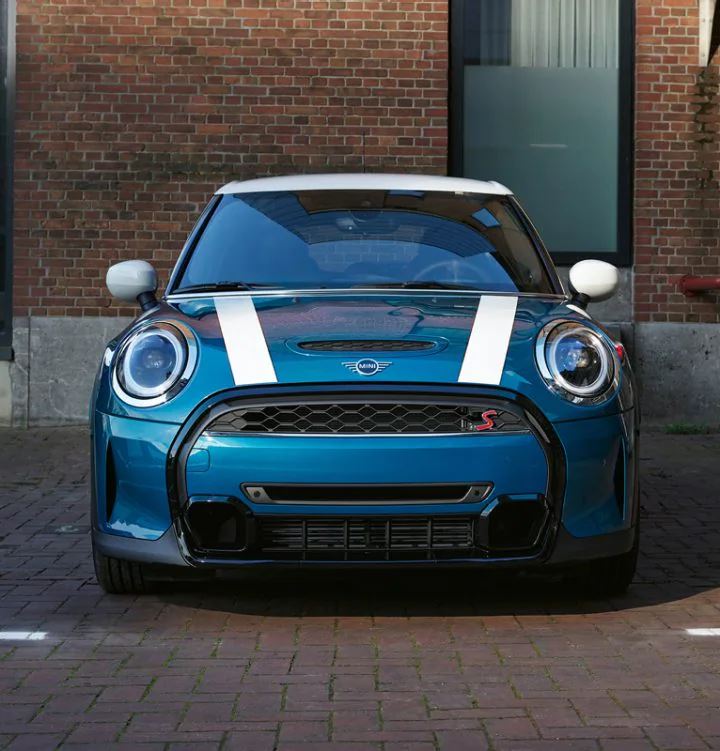 A front view of the MINI Hardtop 4 Door parked in front of a brick building.