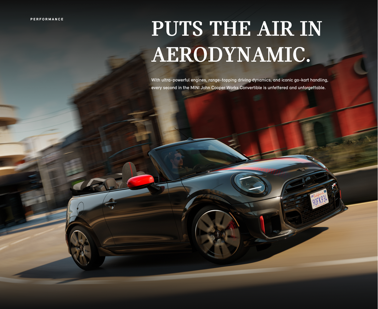 Angled view of John Cooper Works Convertible driving on city street with blurred building in background