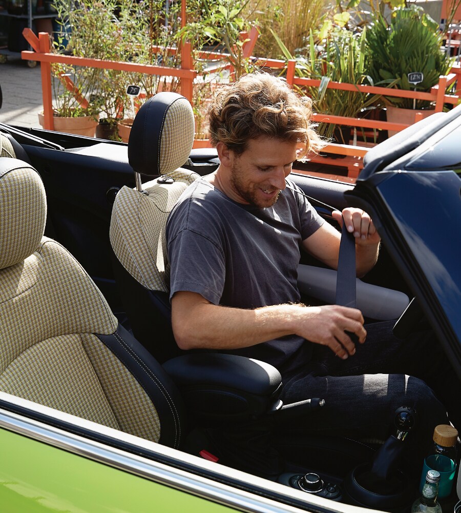Image-4.png Man buckling himself in to a zesty yellow MINI Convertible