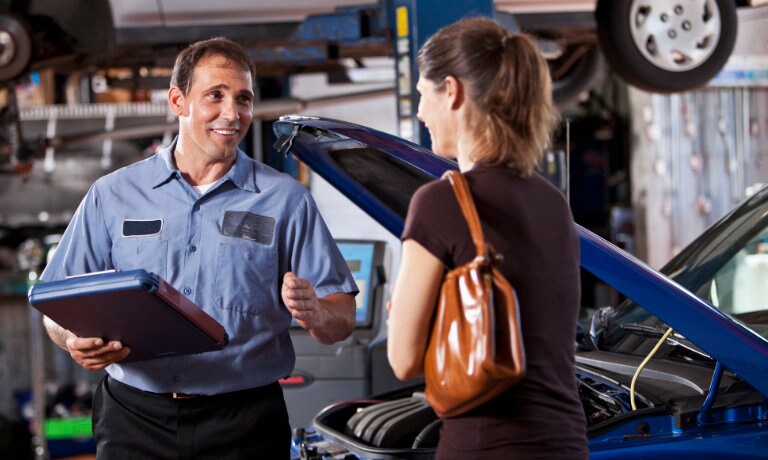woman talking to mechanic while haveing vehicle getting looked at