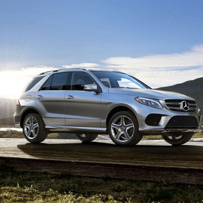2019-Mercedes-GLE-at-Mercedes-Benz-of-Colorado-Springs.png The passenger side of a silver 2019 Mercedes-Benz GLE SUV parked on a small wooden platform with a small body of water in the background at the base of a mountain range as the sun rises over the mountains
