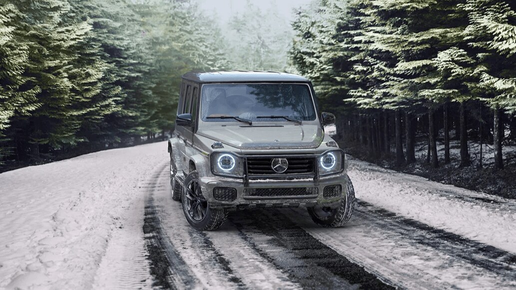 Learn about the off-road capabilities of the Mercedes-Benz G-Class SUV Rendered image of a Mercedes-Benz G-Class SUV driving through a snow-covered forest road