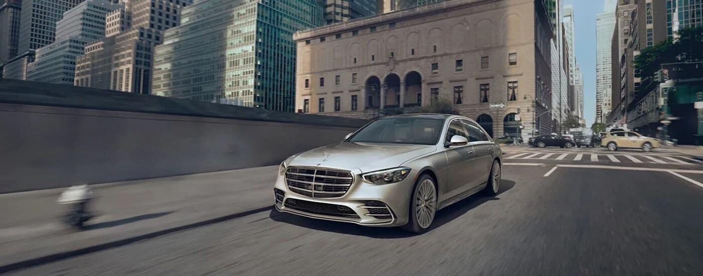 A silver 2023 Mercedes-Benz S-Class is shown on a city street after leaving a Mercedes-Benz dealer near you.
