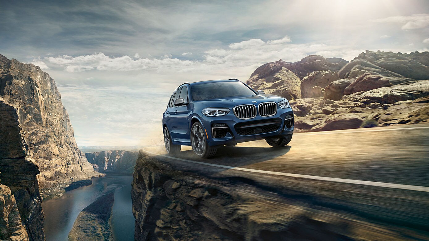 blue BMW X3 driving in an arid environment