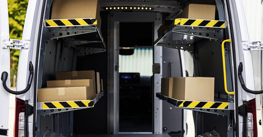 Open rear doors of a Sprinter Cargo Van fitted with fold-down shelves and loaded with cardboard boxes