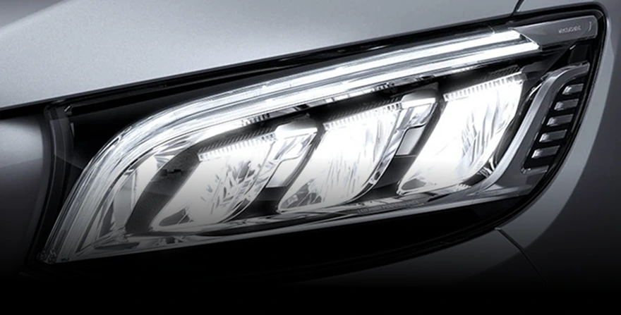 Close-up of an illuminated LED Performance headlight on a grey Mercedes-Benz Sprinter
