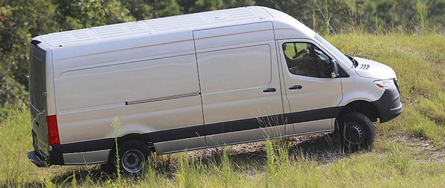 Silver Mercedes-Benz Sprinter Cargo Van driving across a grassy hillside