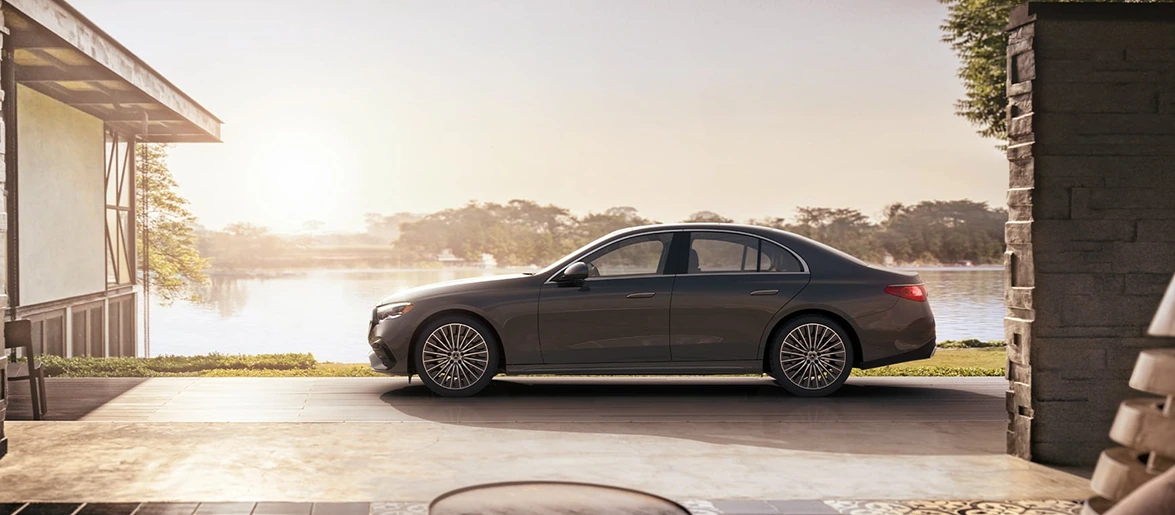 Dark E-Class Sedan parked beside a lake at sunset