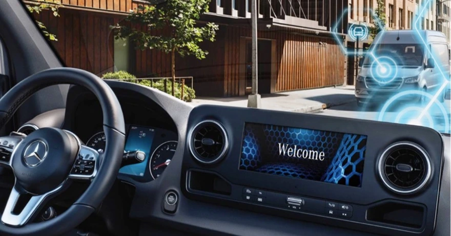 Sprinter cockpit with the multimedia screen showing a Welcome graphic and blue connectivity effects over the street outside