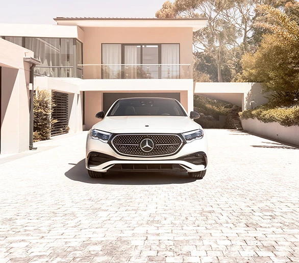 White E-Class Sedan parked in front of a modern home