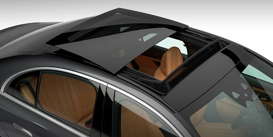 Dark E-Class Sedan seen from above with its panorama roof open over a tan interior