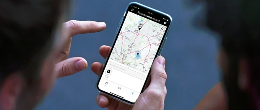 Hand holding a phone showing the Mercedes me connect map with the van's location pinned