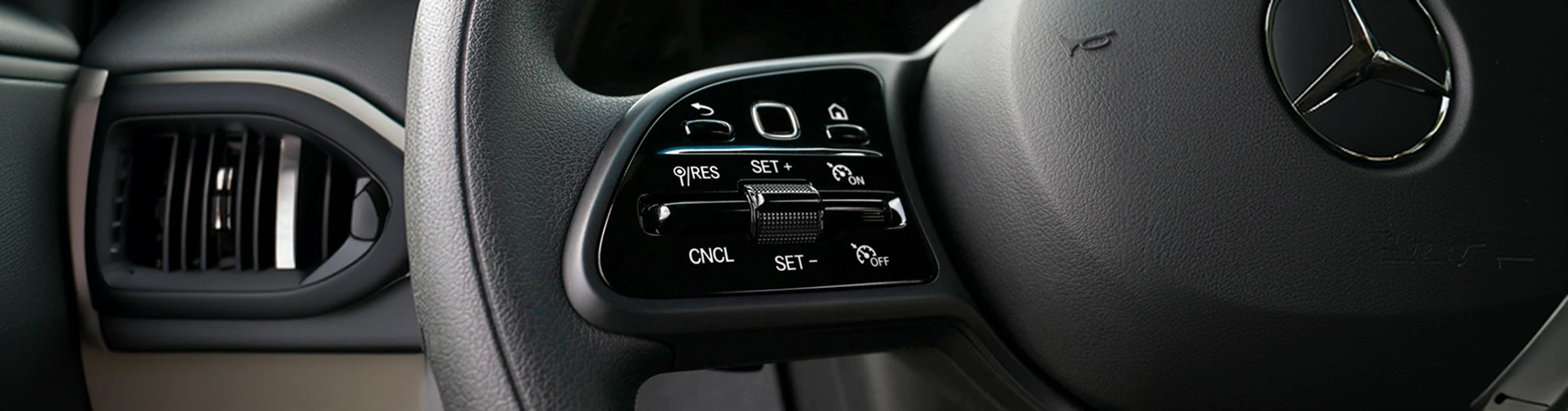 Cruise control buttons on the left spoke of the Sprinter steering wheel, with the Mercedes-Benz star at the hub