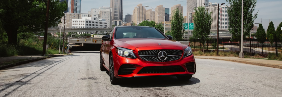 Red MB C-Class driving out of city