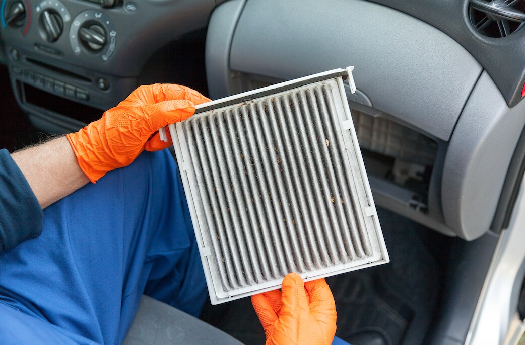 Mechanic removing dirty cabin air filter from vehicle.