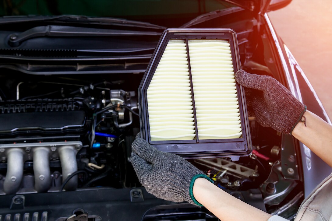 Mechanic holding new engine air filter.