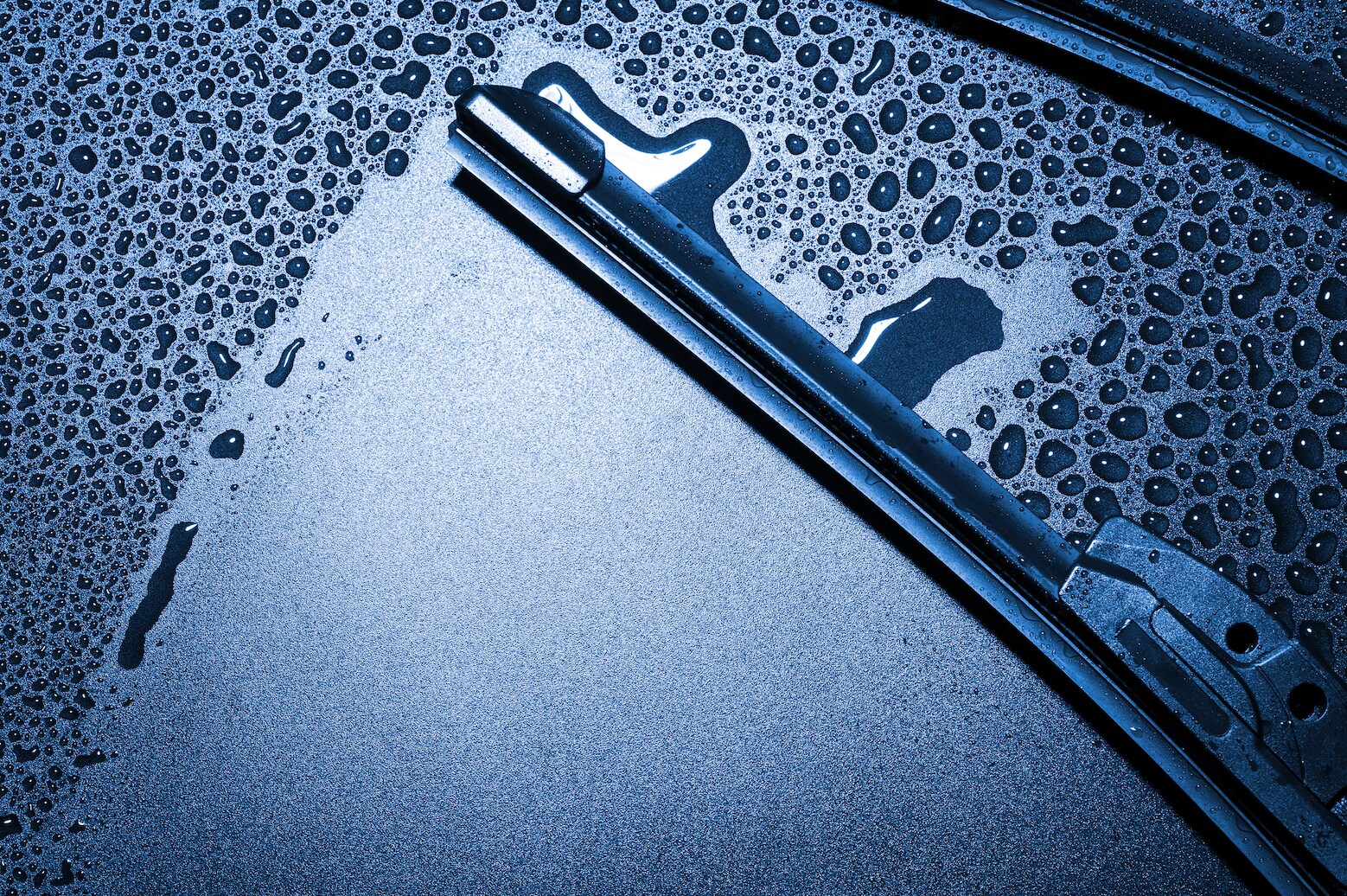 Windshield wiper removing raindrops from windshield.