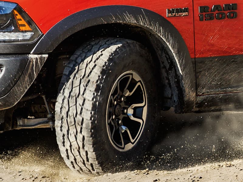 Ram 1500 The tire of a red Ram 1500 driving through the dirt