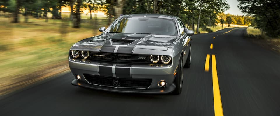2019 Dodge Challenger A silver 2019 Dodge Challenger with black stripes driving down an open country road
