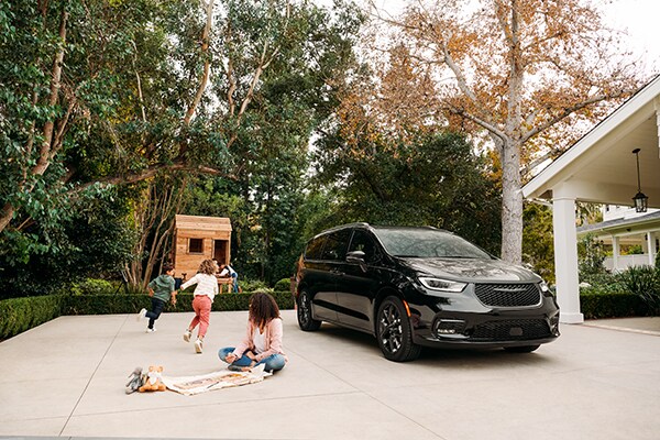 Kids playing in a driveway with a Pacifica parked nearby