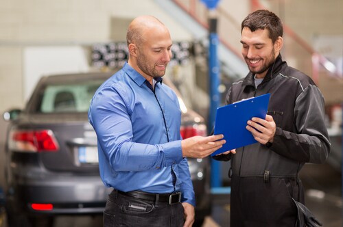 Automotive technician discussing maintenance work on a Ford