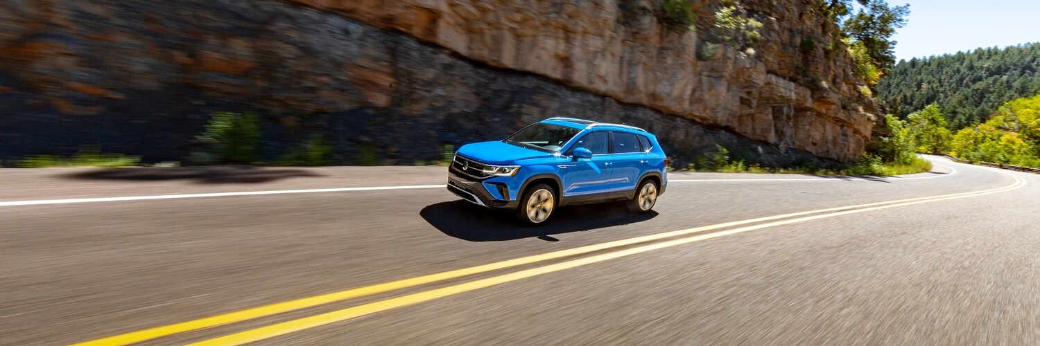 VW Taos side view of a blue Volkswagen Taos SUV driving on the road