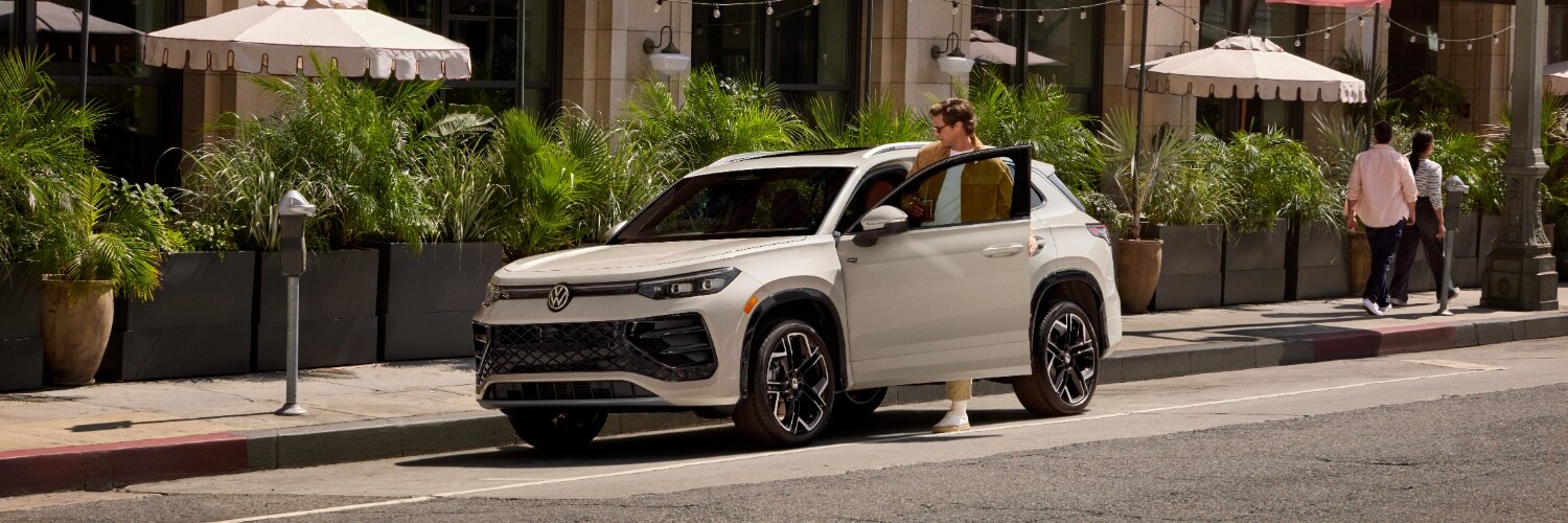 Volkswagen Tiguan Man stepping into a parked White VW Tiguan