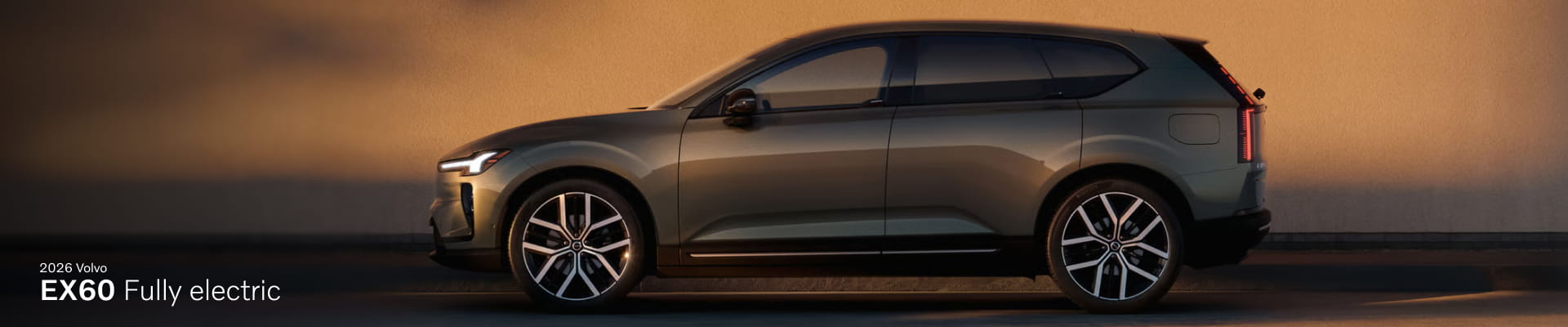 Side view of a sleek, modern 2026 Volvo EX60 electric SUV against a warm, sunset-lit backdrop.