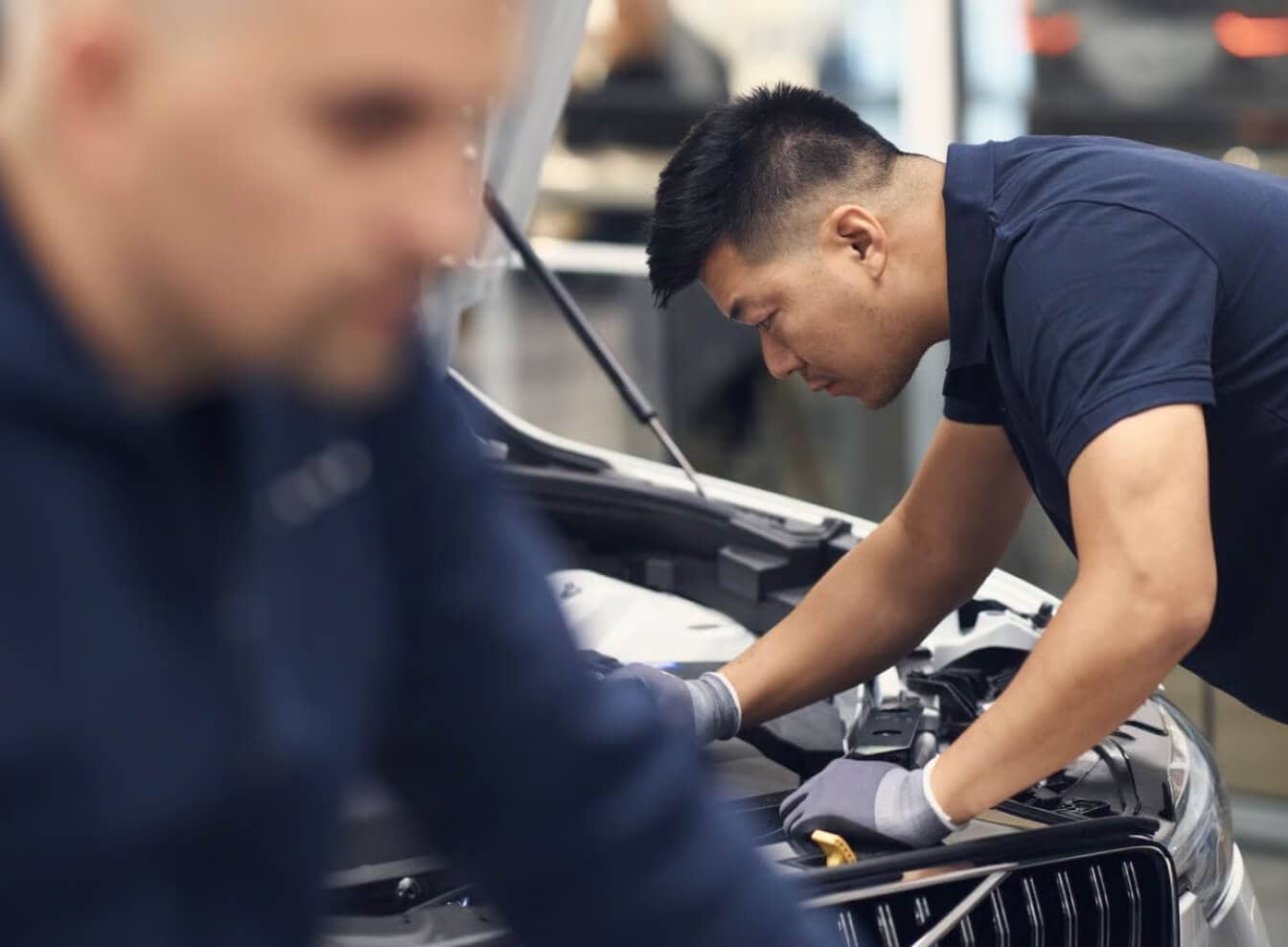 Technician working under the hood of a Volvo vehicle