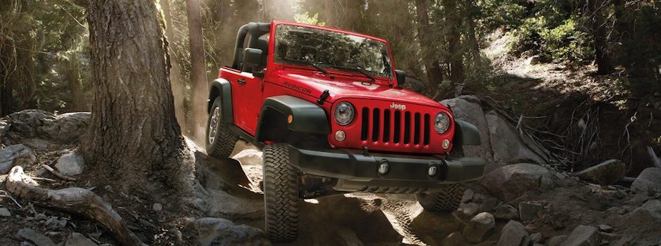 What We Test A red 2018 Jeep Wrangler driving through a rocky forest