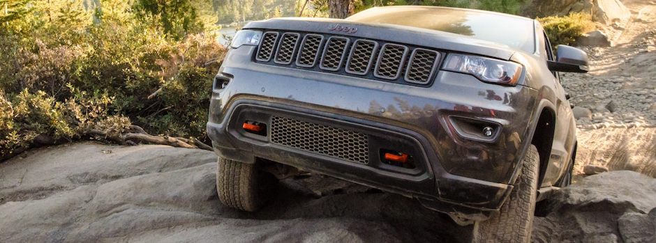 Why We Test A Jeep Grand Cherokee driving up a steep, rocky hill