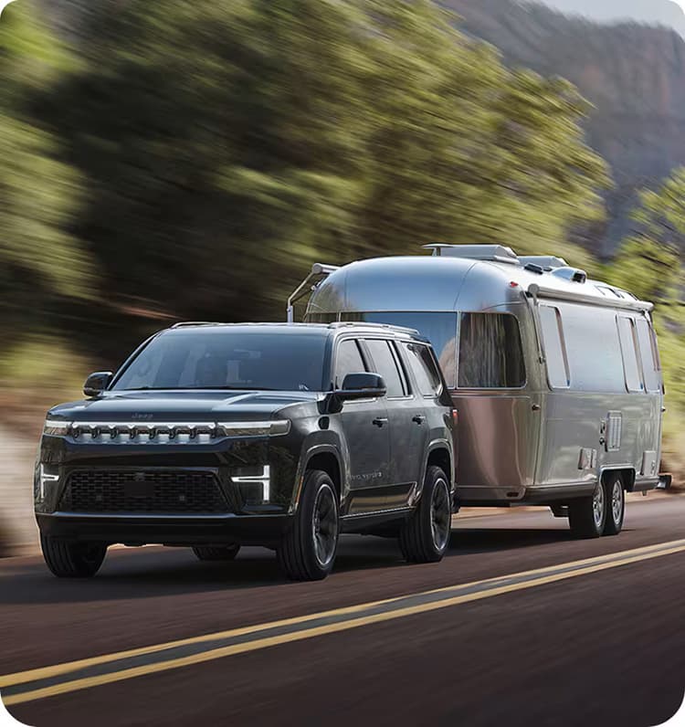 New Jeep Grand Wagoneer Jeep Grand Wagoneer in motion towing a camper on the road