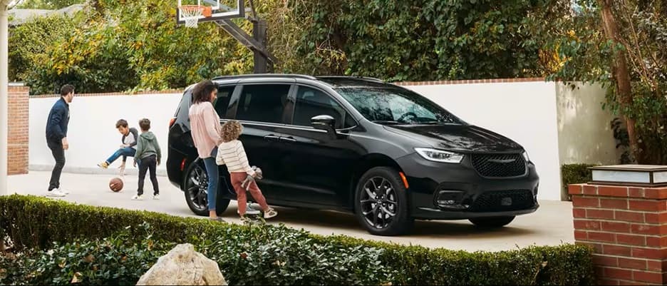 Chrysler Pacifica For Sale in Orlando mom and daughter looking at chrysler pacifica minivan parked in driveway while dad and boys play basketball nearby
