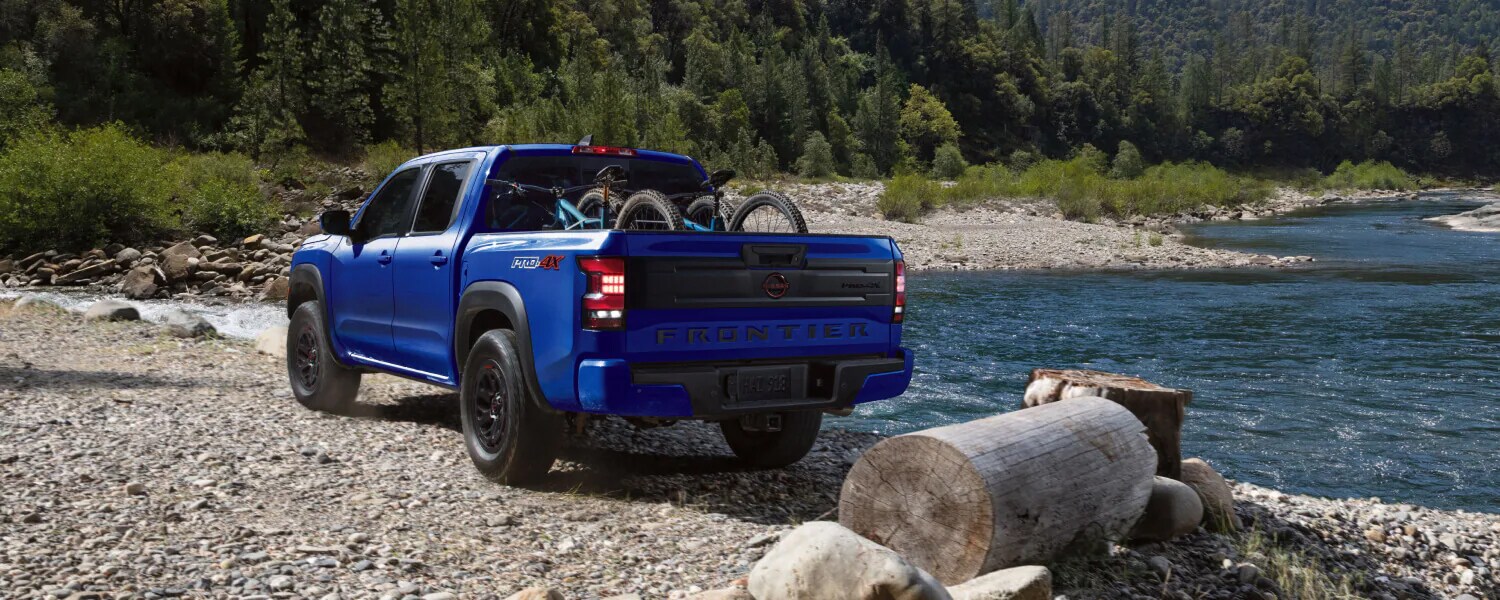 Nissan Frontier parked near a river bank with two bicycles in the trunk