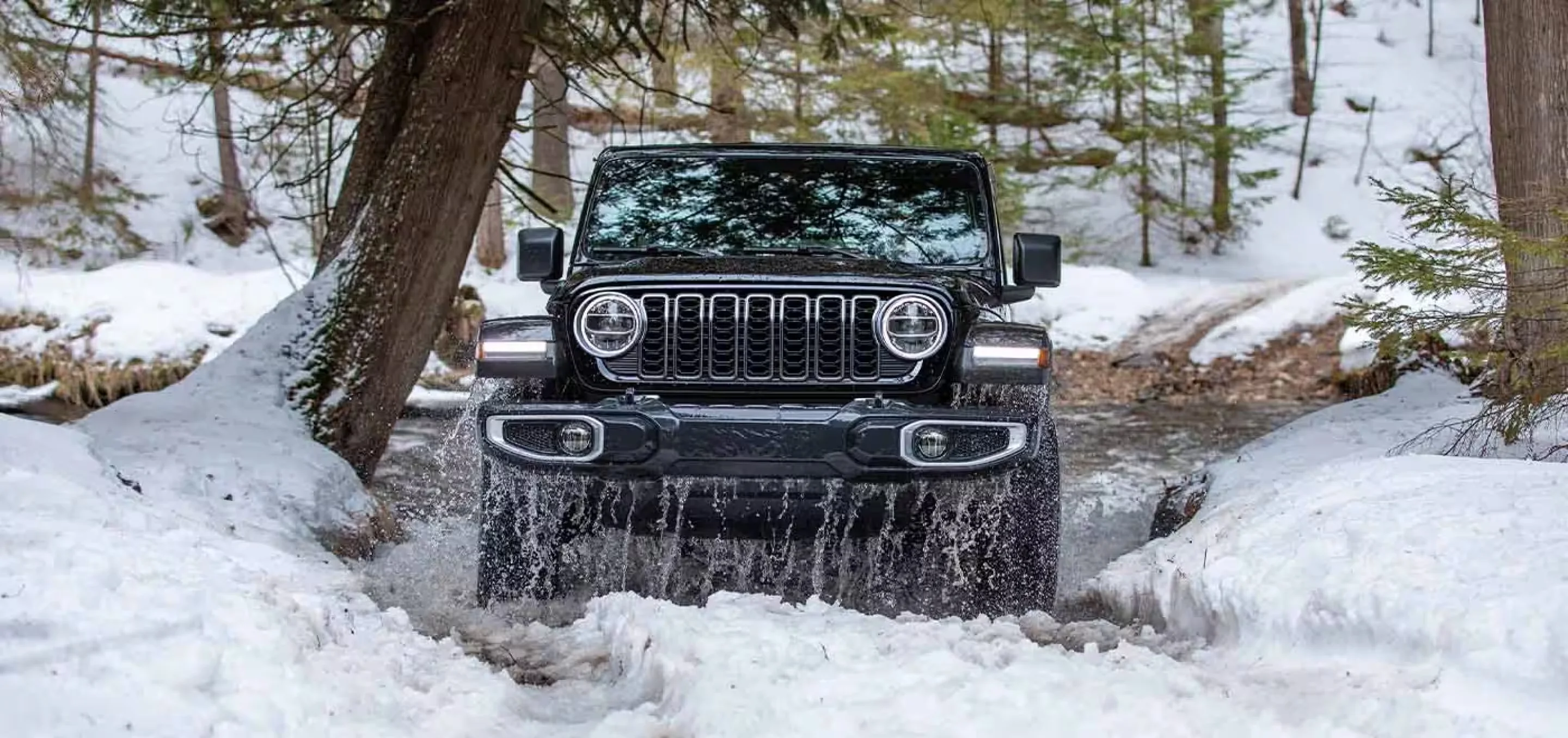 Black Jeep Wrangler Sahara coming out of a water crossing, the kind of use that makes an undercarriage inspection matter on a used Wrangler
