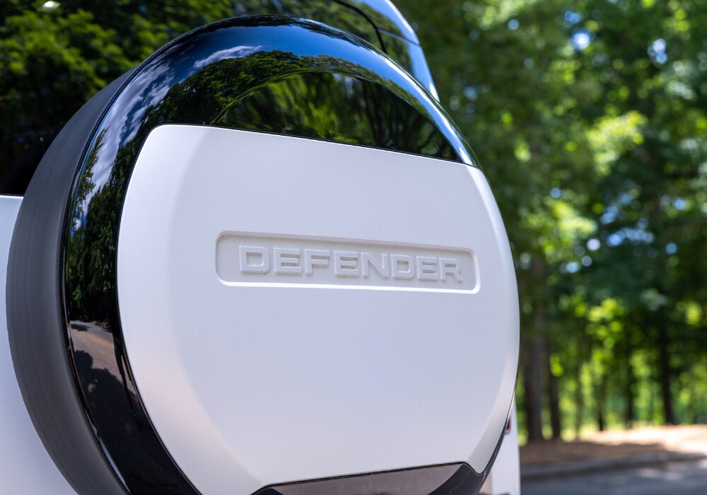 defender-suv-for-sale.png Spare tire cover on the back of a Defender 130. The car is white and the tire cover has the word defender written on it