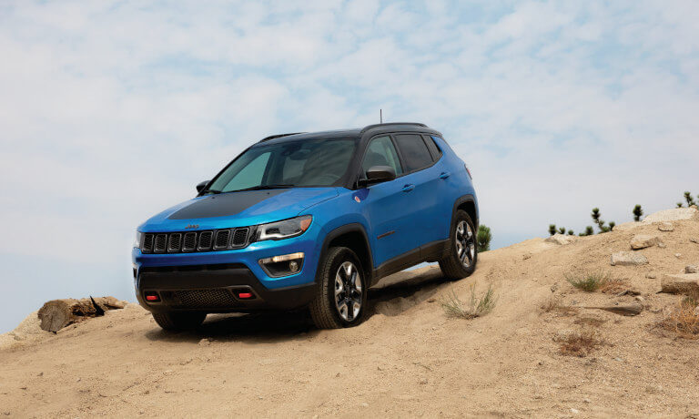 Jeep Compass in blue driving down hill road off road in the desert