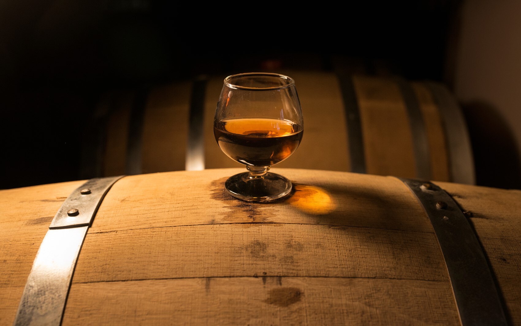 Glass of liquor on distilling barrel at distillery.jpg