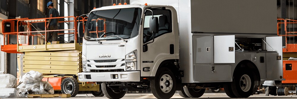 Side of white Isuzu NPR with a trailer next to it