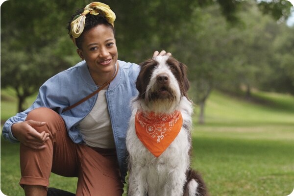 Lady with her dog that is wearing a orange neckerchief