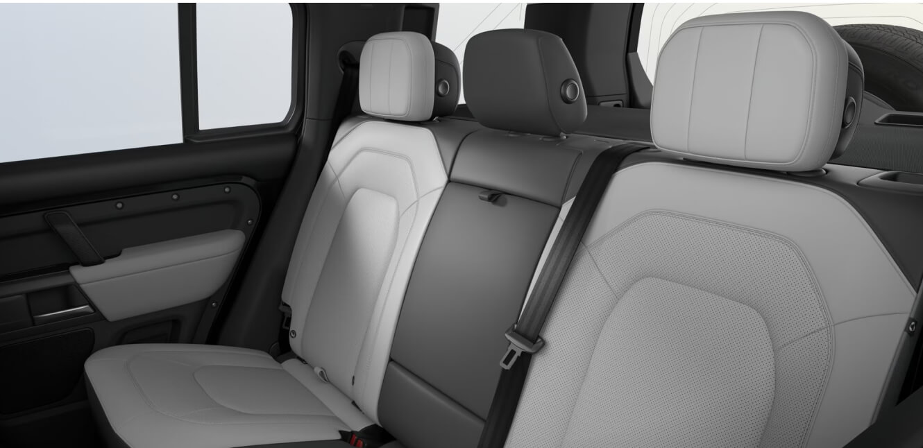 Interior rear passenger row view of a Land Rover Defender 110 V8 showing Light Cloud and Lunar Ultra fabrics interior.