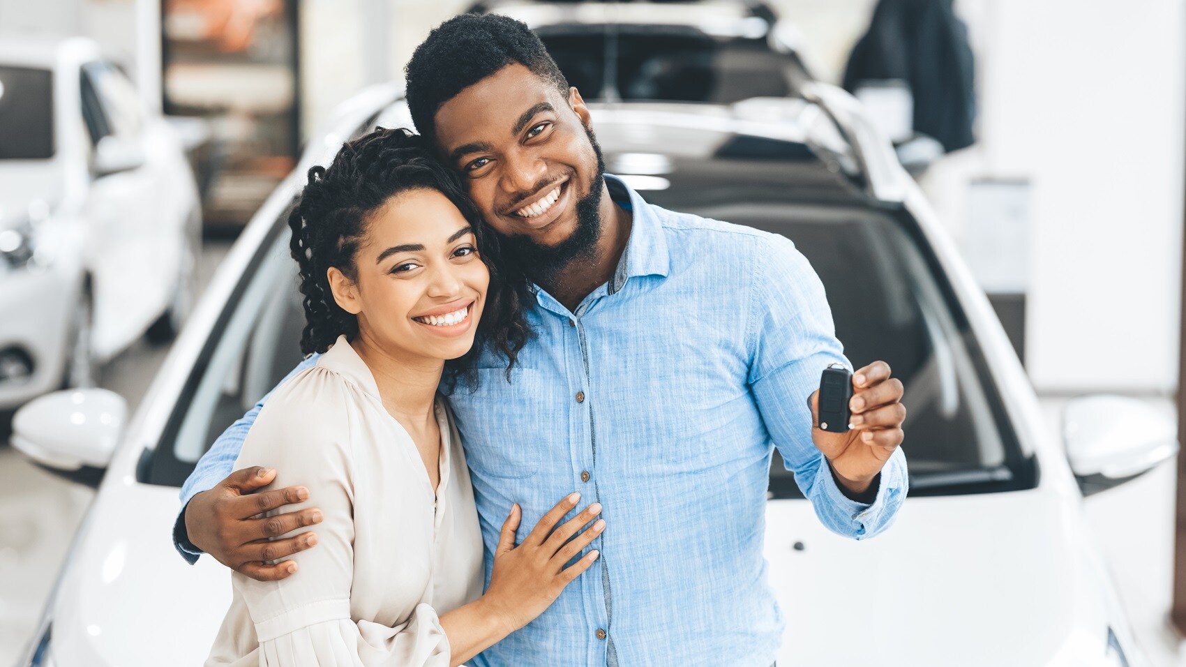 Couple posing for camera smiling and holding up keys for new used vehicle from Used Car Dealer Near La Mesa CA