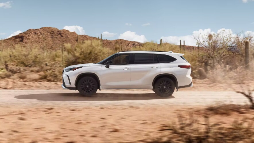 New Toyota Highlander vs. Honda Pilot 2023 White toyota highlander side view driving in desert