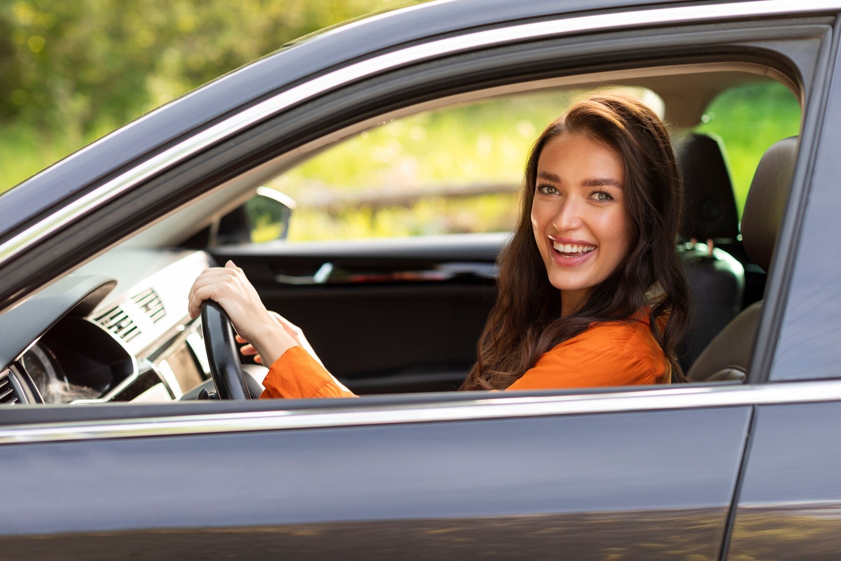 Woman sitting in the driver's seat of a Gold Certified Ford vehicle while smiling at the camera