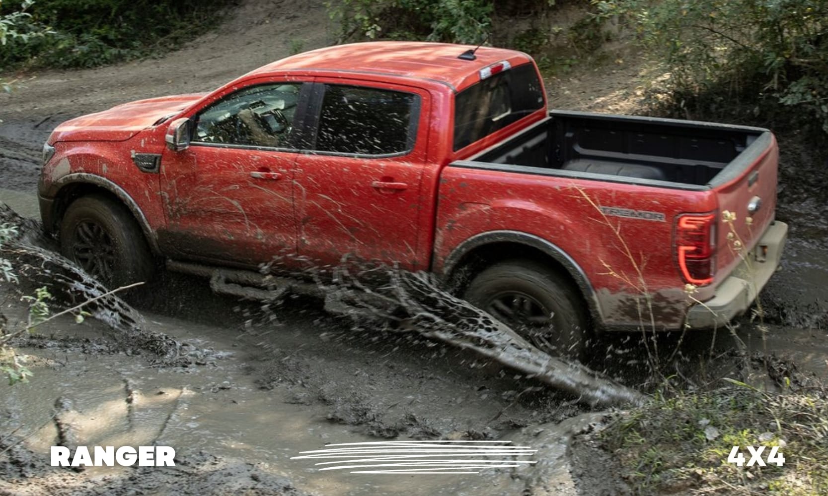 Driver side exterior view of a red Ford Ranger Tremor 4x4 truck powering through some heavy mud with ease on an off-road forest trail