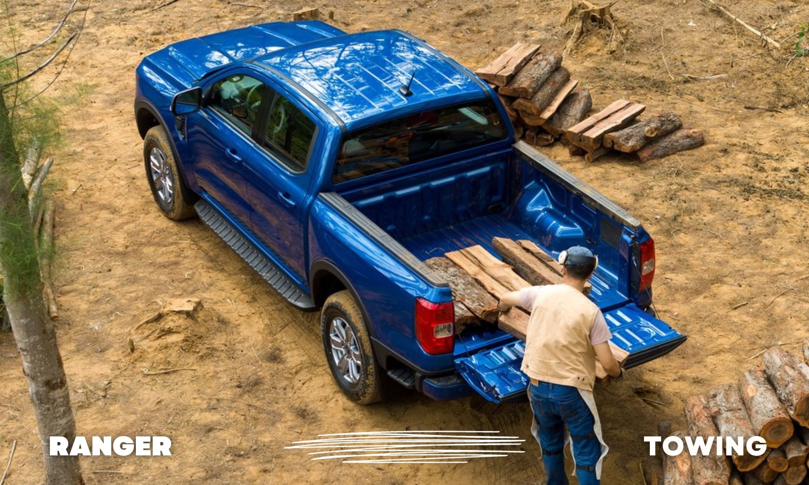 Aerial view of a blue Ford Ranger truck with a man chopping wood and loading the wood blocks into the truck bed